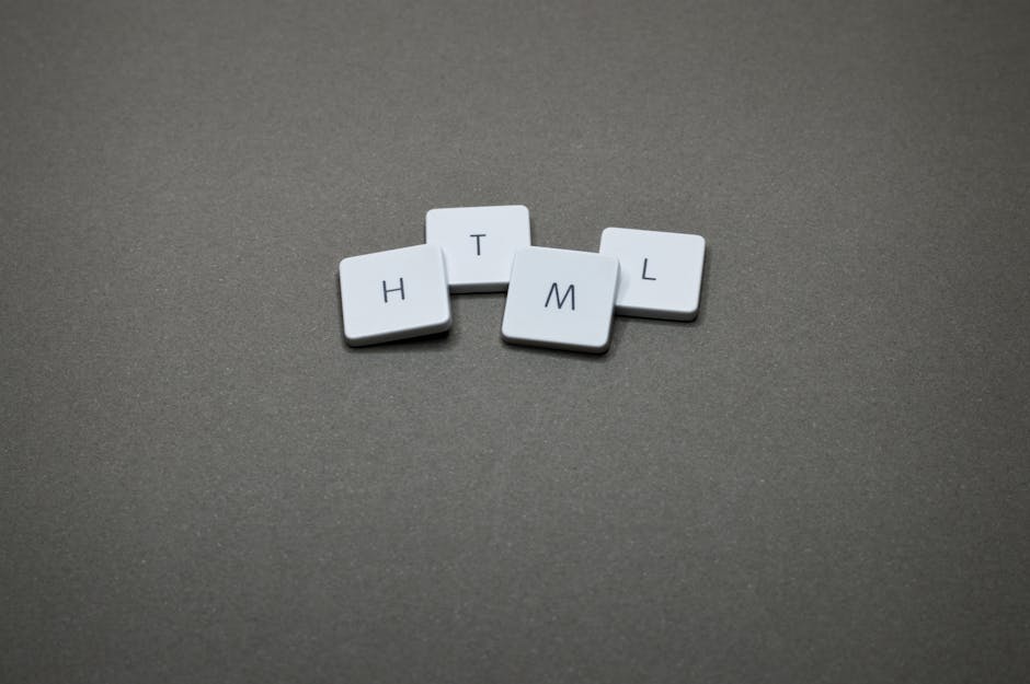 A close-up photograph of four small, white, rectangular tiles with rounded edges arranged on a smooth, dark grey surface. Each tile displays a single black letter: H, T, M, and L, with the tiles posit